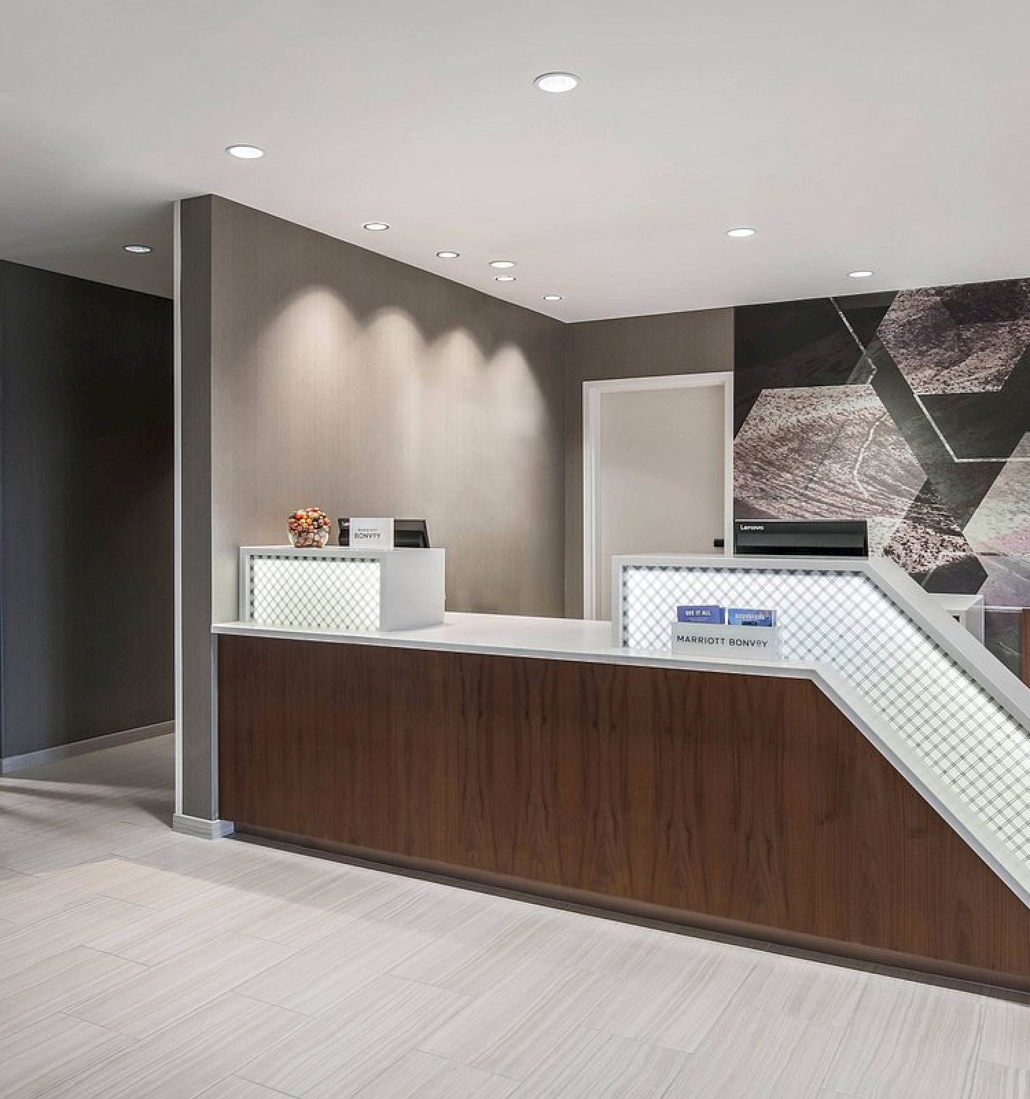 The image shows a modern reception area with a front desk, wall art with hexagonal patterns, and minimalist décor, giving a sleek and professional look.