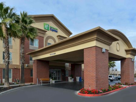 This image shows the entrance of a Holiday Inn Express hotel with an overhang and some landscaping elements near the entrance.