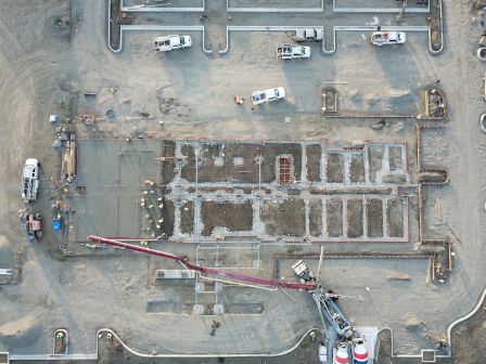 An aerial view of a construction site with vehicles, concrete structures, and construction machines in operation.